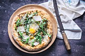 Pizza mit Rucola, Spiegelei und Parmesan (Aufsicht)