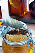 A glass jar of organic honey with honeycomb and a honey spoon