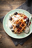 Round Belgian waffles with cream, cherries and chopped pistachios