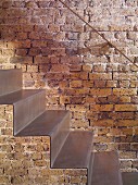Close-up of self-supporting sheet-steel staircase against restored brick wall