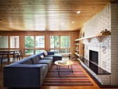 Long blue couch in front of open fireplace in pale brick wall