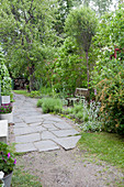 Irregular, stone-flagged path in lush garden