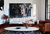 Classic, oval coffee table, couches, arc lamp and large format painting in the living room