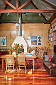 Esstisch mit Stühlen, Vintage Ledersofa und Bücherregal in hohem Wohnraum mit Kamin und Holzlager an Kassettenvertäfelung
