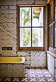 Bathtub in vintage bathroom with pressed metal panels in former stable
