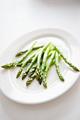 Uncooked green asparagus on a white serving platter