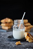 Milk with a straw in a screw top jar and stacks of waffles