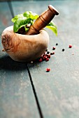 Fresh basil leaves in mortar on wooden table