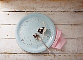 An empty plate with remains of a slice of cake (top view)