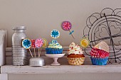 Cupcakes, paper cases and colourful decorations on a kitchen shelf