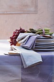 Green asparagus, grapes and fabric napkins on a pile of plates