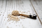Quinoa auf Löffel und weißem Holzuntergrund