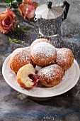 Icing sugar being sifted over a plate of jam doughnuts