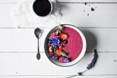 A smoothie bowl with fruits, edible flowers and gluten-free muesli (seen from above)