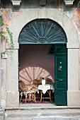 Traditional arched entrance with open, dark-green double doors
