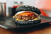 Black burger with cheese, tomatoes and lettuce