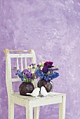 Blumen in Rotkohlköpfen auf Vintage Holzstuhl mit weißen Vogelfiguren