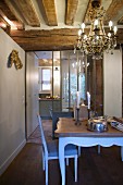 Chandelier, lit candles and rustic wood-beamed ceiling in dining area