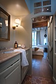 View from illuminated bathroom into bedroom with traditional ambiance