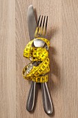 A knife and fork wrapped with measuring tape