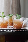 Trauben-Mocktail mit Eiswürfeln und Minze in Gläsern auf Tablett