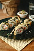 Sushi rolls with salmon, deep fried in tempura batter, on a black plate