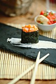 Einzelnes Sushi mit Lachstatar auf schwarzer Platte