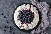 Homemade meringue cake Pavlova with whipped cream, fresh blueberries and blueberry sauce on vintage cake stand