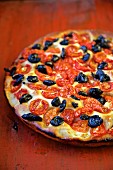 Focaccia with Tomatoes and Olives on a red table (Italy)