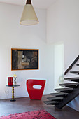 Red designer easy chair at foot of self-supporting staircase