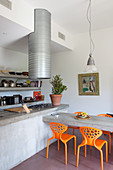 Concrete table and colourful plastic chairs in industrial-style kitchen