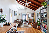 Table with two chairs and bookcase, lounge with vintage seating in the background