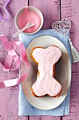 Carrot cake in the shape of a bone with pink fresh cheese for dogs