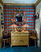 Old chest of drawers and wooden chairs against tartan wall in chalet