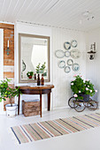 Console table and mirror in hall with decorative wall plates and potted geranium