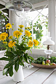 Vase of yellow Calliopsis and peony leaf