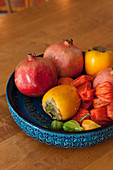 Blue bowl with structure surface holding exotic fruit in shades of red