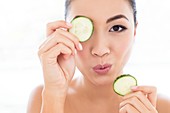 Woman holding cucumber in front of eye