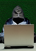 Hooded figure hacking laptop computer