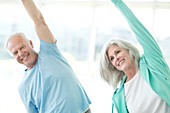 Senior couple stretching arms upwards