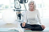 Senior woman sitting cross legged in gym