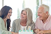 Senior couple and adult daughter with birthday cake
