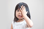 Young girl covering eye with hand