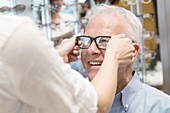 Optician putting glasses on senior man