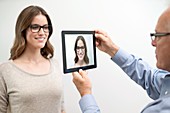 Man holding digital tablet in front of woman's face