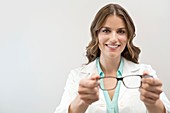 Female optician holding glasses