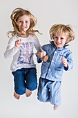 Sister and brother jumping on bed