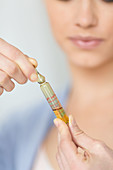 Woman holding glass ampoule of vitamin D