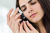 Woman applying essential oil on a neutral pill