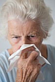 Elderly woman blowing her nose